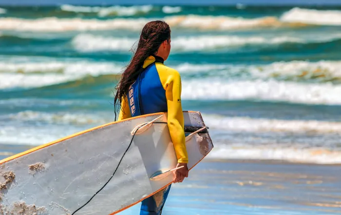 Surferin in Neoprenanzug mit Surfbrett im Surfcamp Mirleft Marokko