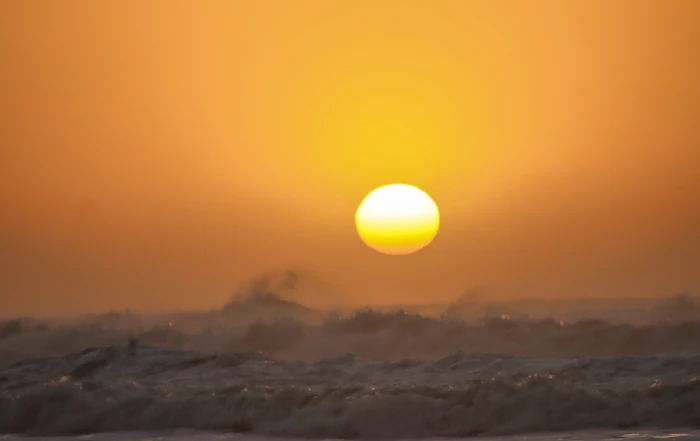 Goldene Abendsonne hinter den rauschenden Wellen von Mirleft, aufgenommen vom Strand.