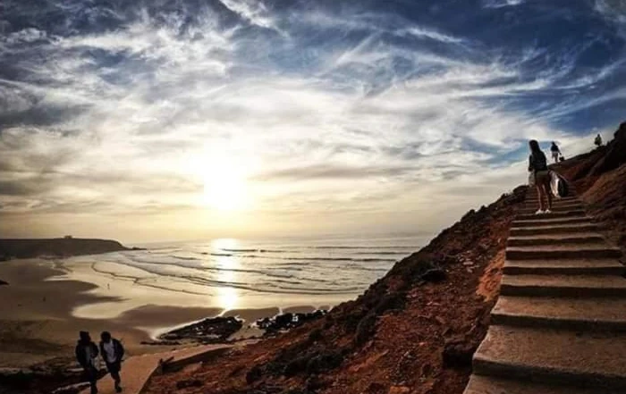 Treppe führt zum Strand von Mirleft, mit weitem Blick auf den Sonnenuntergang über dem Atlantik.