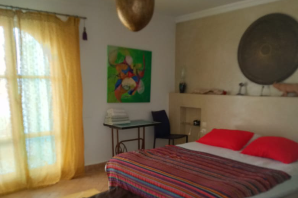 Schlafzimmer mit Deko, Schreibtisch und buntem Bettbezug im Surfcamp Mirleft