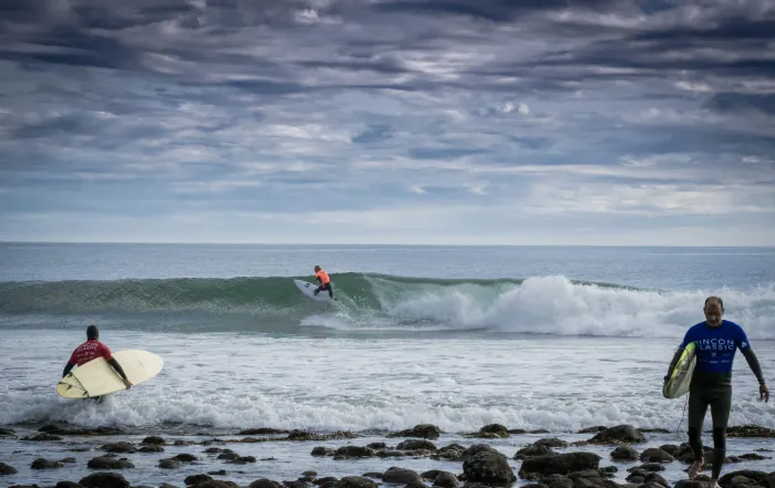 Drei Surfer bei rauen Bedingungen an der Küste von Mirleft im Karma Surf Camp